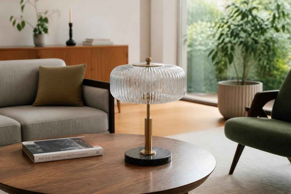 Szklana lampa stołowa na okrągłym drewnianym stoliku w salonie z sofą i roślinami
